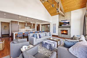 Living room with dark wood-style flooring, a high wooden ceiling, and a fireplace