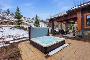 Snow covered patio featuring a patio area, outdoor dining area, and an outdoor hot tub