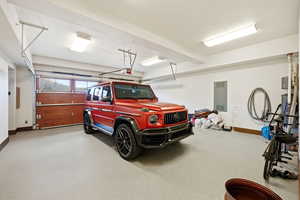 Garage featuring baseboards and electric panel