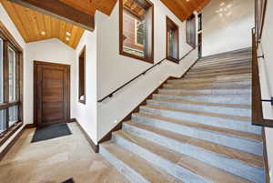Stairway featuring recessed lighting, a high wooden ceiling, and stone finish flooring