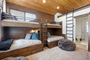 Bedroom with wooden ceiling, wood walls, a barn door, recessed lighting, and connected bathroom