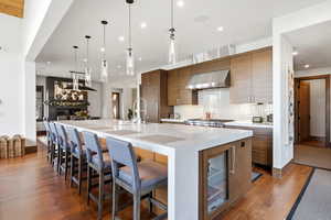 Kitchen with light stone countertops, a large island, modern cabinets, dark wood finished floors, and a breakfast bar