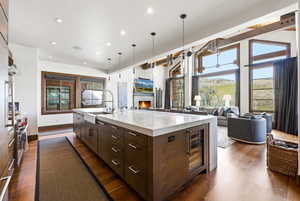 Kitchen featuring dark wood finish cabinets, a fireplace, open floor plan, a large island, and light stone countertops
