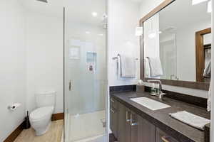 Bathroom featuring vanity, a stall shower, recessed lighting, and light wood-style flooring