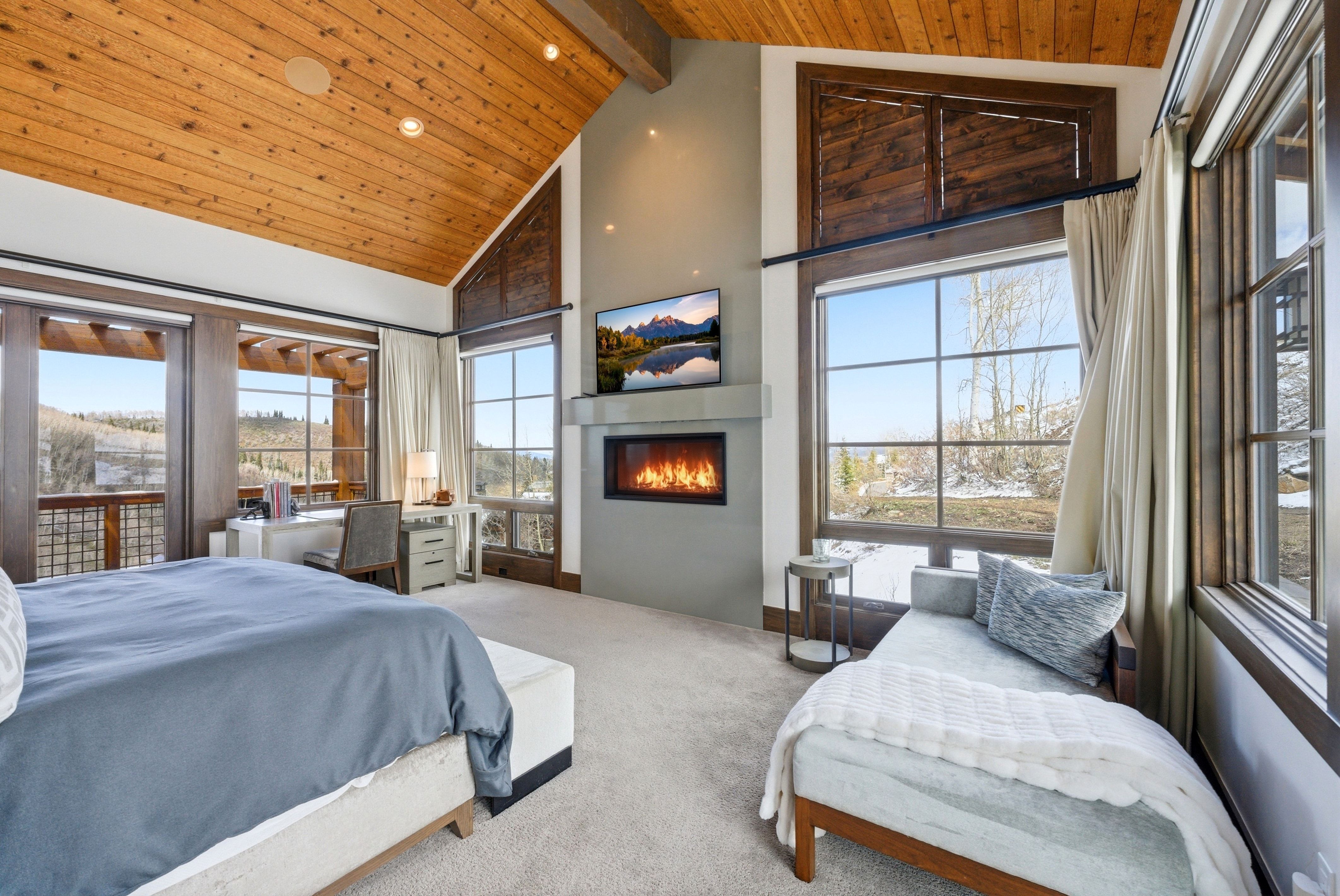 Bedroom with carpet floors, a glass covered fireplace, a high wood beamed ceiling, and recessed lighting