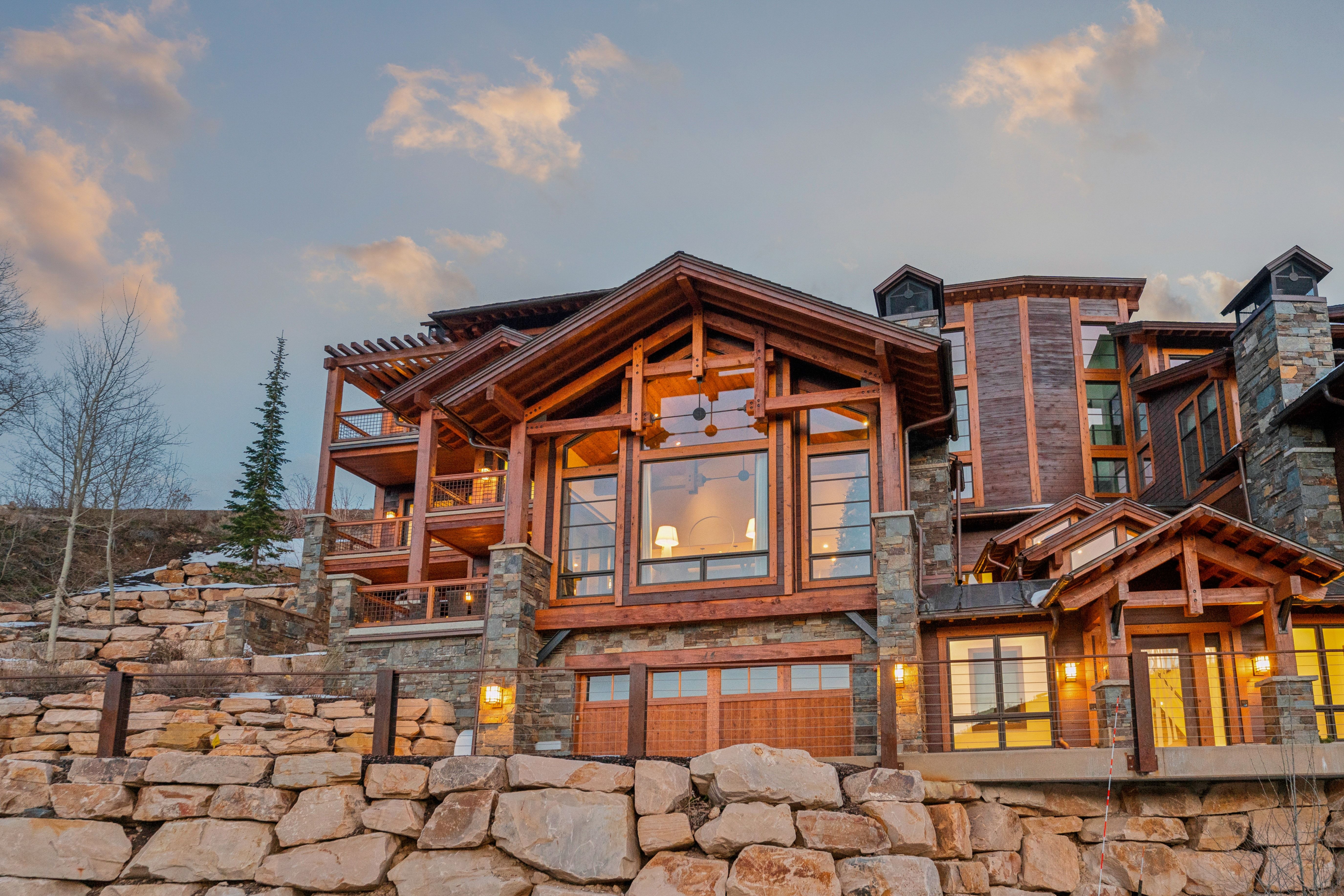 Back of house featuring stone siding and a balcony