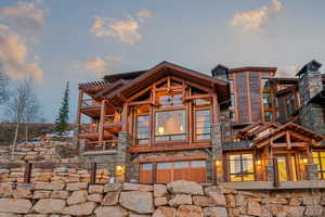 Back of house featuring stone siding and a balcony
