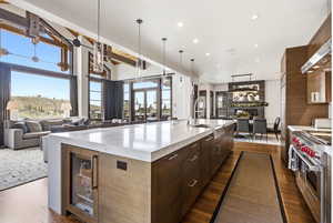 Kitchen featuring modern cabinets, open floor plan, dark wood finish cabinets, light stone countertops, and range with two ovens