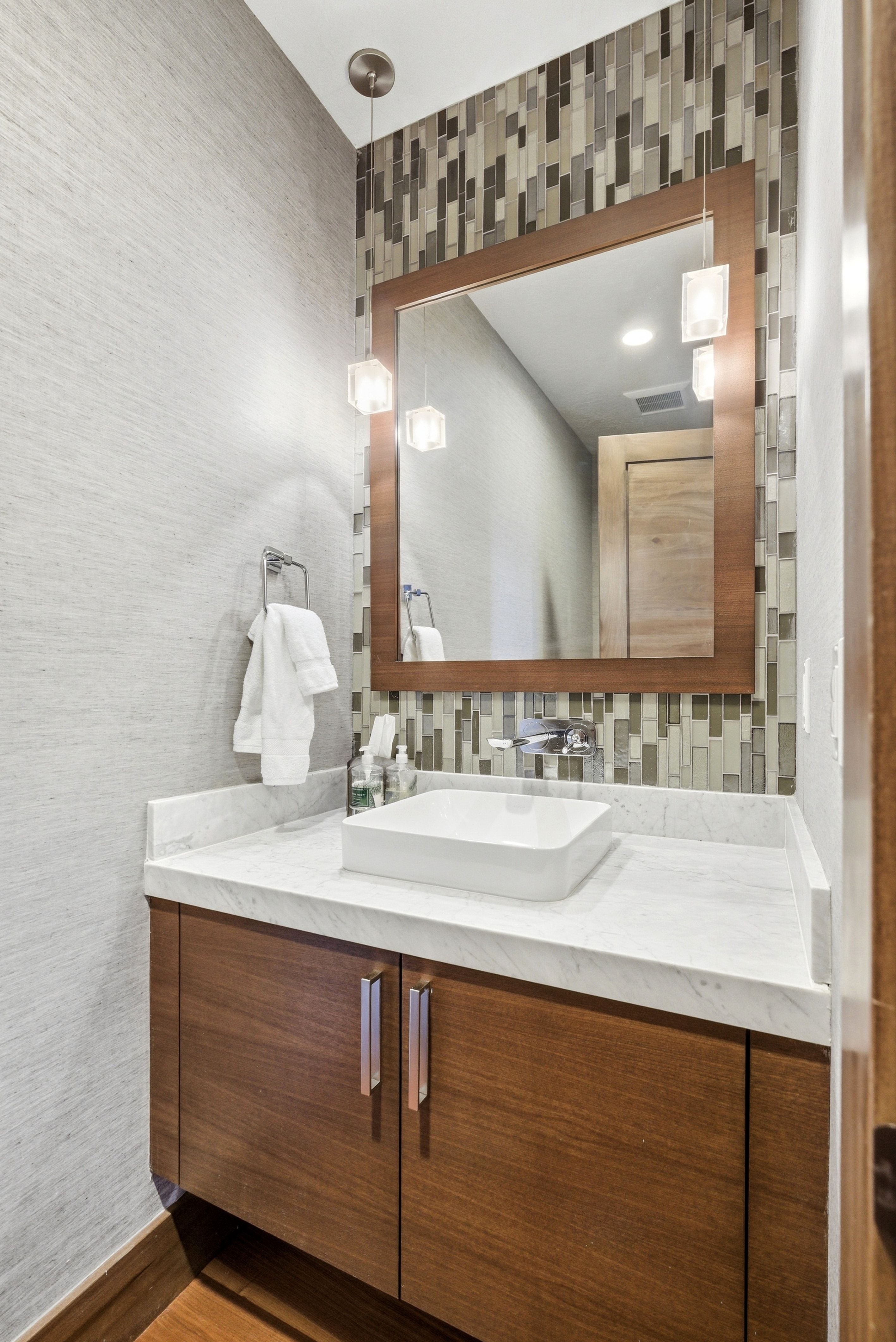 Bathroom with vanity, decorative backsplash, wood finished floors, and wallpapered walls