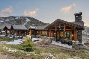 Rear view of property featuring stone siding, a patio area, and a mountain view