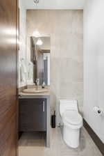 Half bath with vanity, tile walls, and light tile patterned flooring