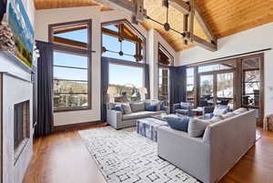 Living room featuring a high wood beamed ceiling, light wood finished floors, a fireplace, and plenty of natural light