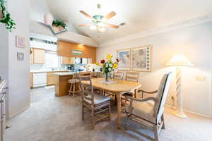 Dining area with a ceiling fan, light colored carpet, and lofted ceiling