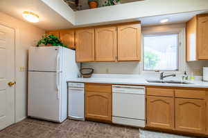 Kitchen with white appliances, light countertops, and light wood finish cabinetry
