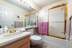 Full bathroom with vanity, dark tile patterned floors, and bath / shower combo with glass door