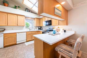 Kitchen featuring light countertops, light wood finish cabinetry, a peninsula, stainless steel electric range, and recessed lighting