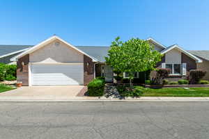 Single story home with brick siding, a garage, driveway, and stucco siding