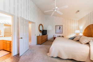 Bedroom with light colored carpet, wallpapered walls, a ceiling fan, and light tile patterned floors