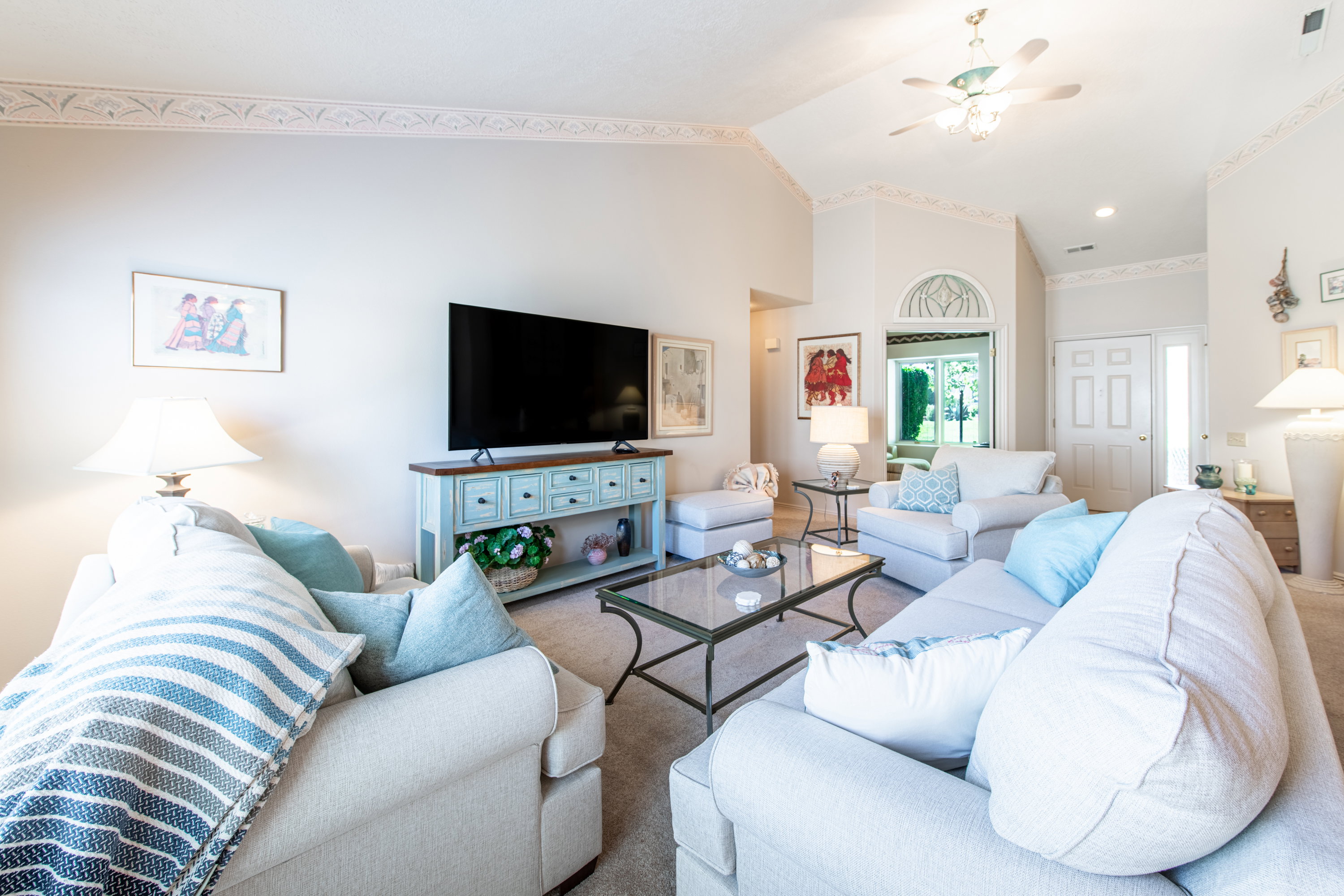 Living room with ceiling fan and lofted ceiling