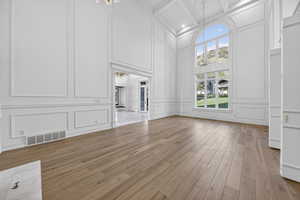 Parlor featuring a decorative wall, a chandeliers, hardwood flooring, and coffered ceiling