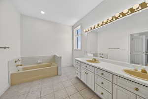 Full bathroom with double vanity, a bath, and light tile floors
