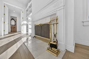 Primary suite fireplace with hardwood flooring and ornamental molding