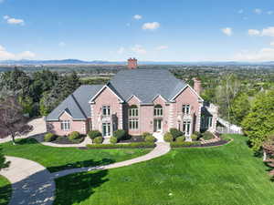 Traditional home featuring brick siding, a chimney, a front lawn, and a shingled roof