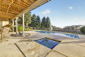 View of pool featuring a fenced backyard, an in-ground hot tub, patio surround, and a water slide