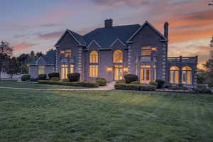 French Provincial style estate with a chimney, a lawn, and brick siding