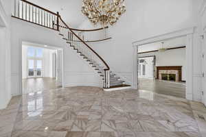 Foyer entrance with a decorative wall, a fireplace, wainscoting, Italian chandelier, and a high ceiling