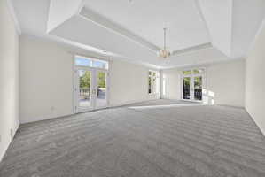Bedroom with french doors, balconies, ornamental molding, carpet, and chandelier