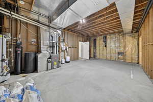 Unfinished basement area featuring a water softener, heating unit, and gas water heater