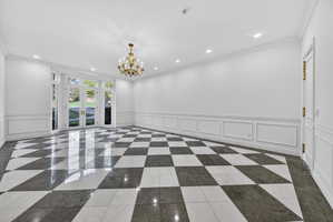 Dining room with a decorative wall, a wainscoted wall, crown molding, chandelier and recessed lighting, and marble floors