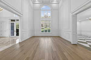 Parlor featuring chandeliers, a decorative wall, french doors, hardwood floors, and a high ceiling