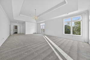 Bedroom with ornamental molding, a chandelier, and light carpet