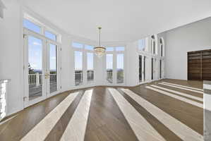 Breakfast nook with hardwood flooring, french doors, chandelier, and a high ceiling
