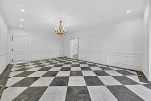 Dining room featuring a decorative wall, wainscoting, chandelier and recessed lighting, ornamental molding, and marble floors