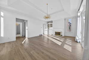 Primary suite featuring chandelier, hardwood floors, built in features, a high end fireplace, and ornamental molding