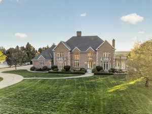French Provincial style estate featuring a front yard, a chimney, brick siding, and a shingled roof