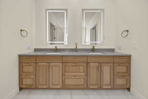 Primary suite bathroom featuring double vanity and light marble finish flooring