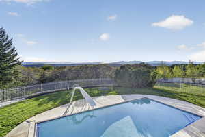 View of swimming pool with a fenced backyard, patio surround, and a water slide