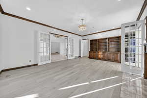 Study with french doors, chandelier, hardwood floors, and crown molding