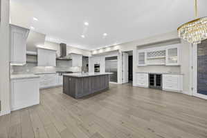 Dual tone kitchen featuring Wolf and Sub-Zero stainless steel appliances, a center island with sink, dual tone cabinets, hardwood flooring, and stone countertops