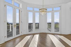 Breakfast nook and doorway to outside featuring hardwood flooring and a chandelier