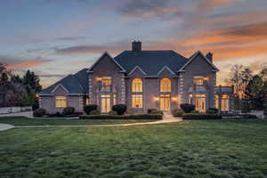 Traditional home with a chimney, a front lawn, brick siding, and a balcony