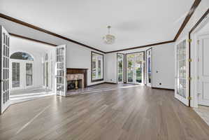 Study with french doors, crown molding, a high end fireplace, and hardwood flooring