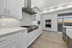 Kitchen featuring stone countertops, Wolf and Sub-Zero stainless steel appliances, hardwood flooring, stone backsplash, and recessed lighting