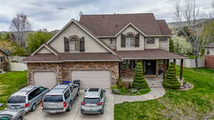 Traditional home with a porch, roof with shingles, stucco siding, and driveway