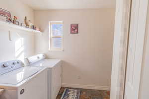 Laundry room featuring separate washer and dryer and dark stone finish flooring