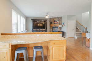 Kitchen featuring light wood-style floors, a ceiling fan, light wood finish cabinetry, and open floor plan